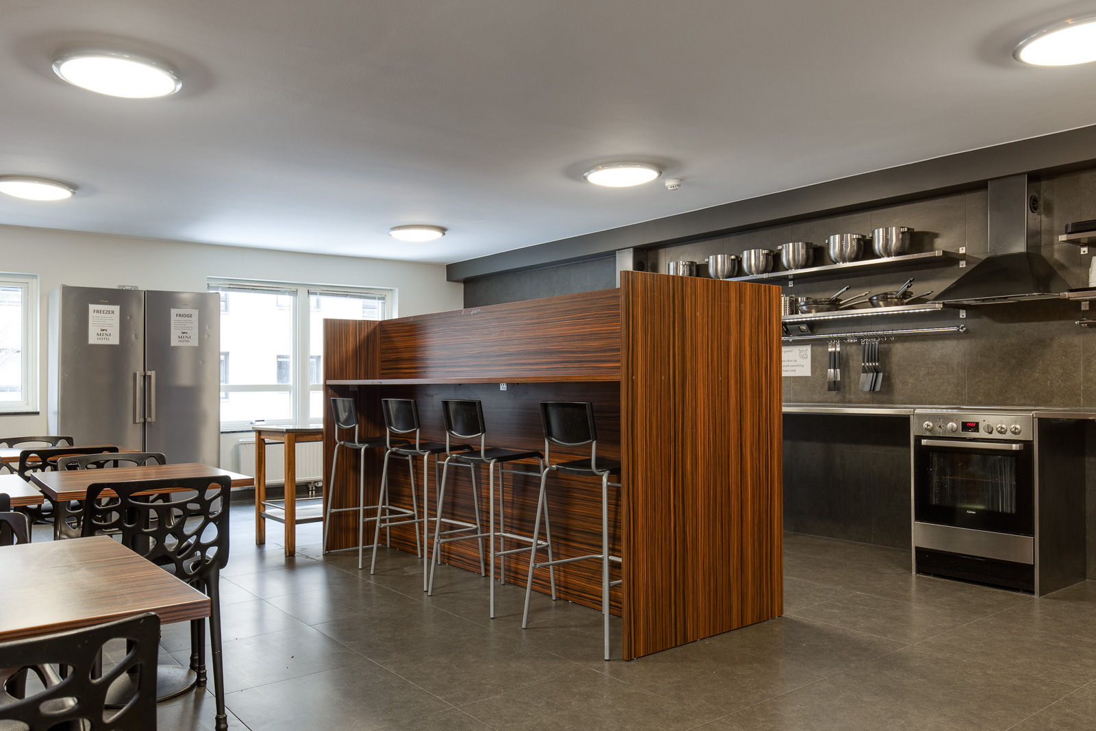 Shared guest kitchen with tables, breakfast bar and oven at Mini-Hotel
